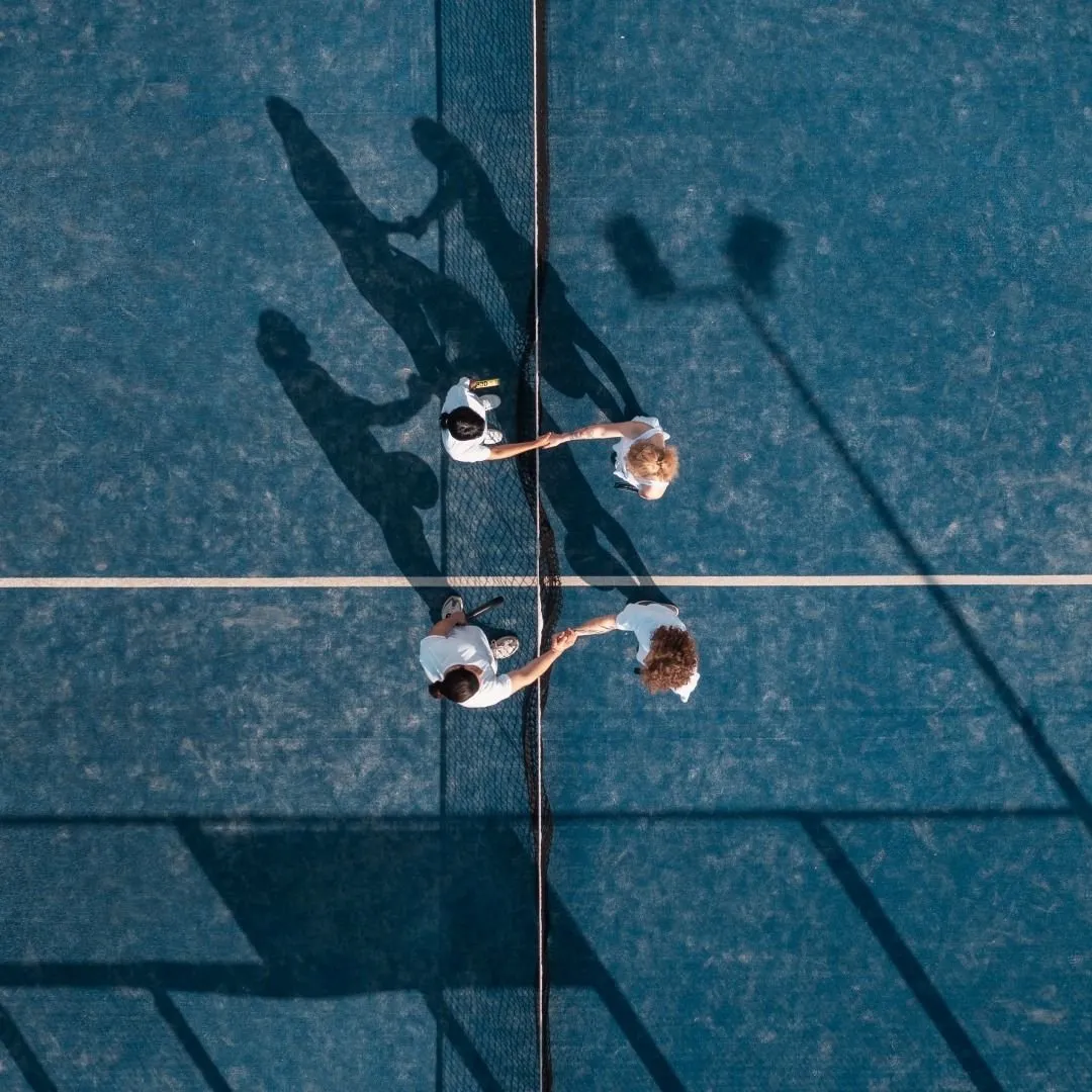 Players on either side of a padel net, seen from above